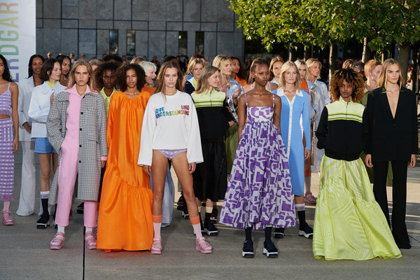 A GROUP OF WOMEN MODELS STANDING OUTSIDE IN COLORFUL DRESSES