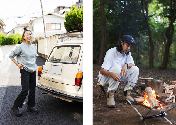 ASIAN WOMAN WEARING A GREY HOODIE BLACK PANTS AND BLACK BOOTS STANDING BEHIND AN OLD CAR AND AN ASIAN GUY WEARING A CAP A WHITE T-SHIRT WHITE PANTS AND BEIGE BOOTS SITTING IN THE WOODS LIGHTING A FIRE
